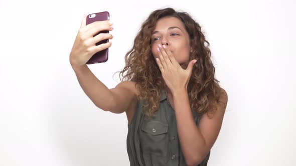 Portrait of Attractive Playful Lady Making Selfie Photo on Mobile Phone Doing Air Kiss Isolated on