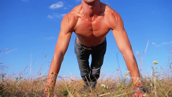 Young Athletic Man with a Bare Torso Performs Push-ups with Claps on Nature. Slow Motion