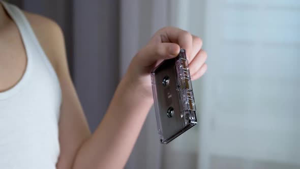 Child Holds an Old Black Vintage Audio Cassette in His Hands Examines It