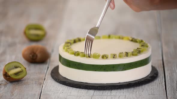 Chef decorate the cake with fresh kiwi. Homemade mousse cake with kiwi.	