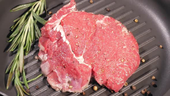 The Meat Steak Is Fried with a Leaf of Rosemary and Peppercorns in a Slowly Rotating Pan