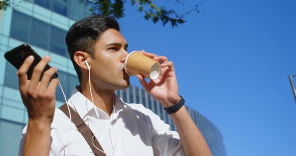 Man having coffee while talking on mobile phone