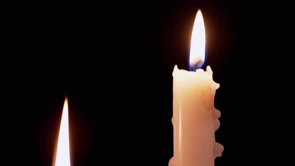 Two White Paraffin Candles Burn with a Calm Yellow Fire on a Black Background