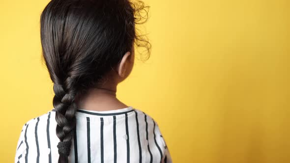 Child Girl with Long Hair Against Yellow Background