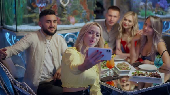 Smiling Slim Beautiful Woman Taking Selfie with Friends Sitting in Expensive Restaurant