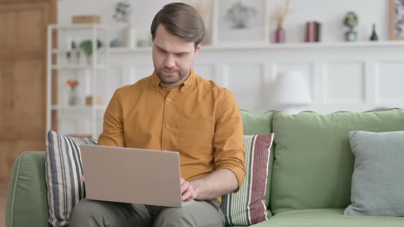 Young Man Closing Laptop, Leaving Sofa