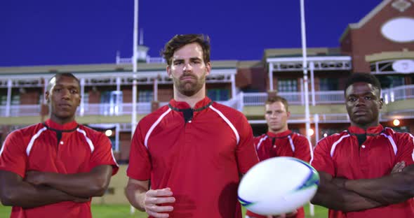 Male rugby players with rugby ball and arms crossed standing in stadium 4k