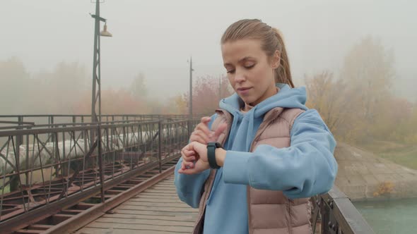 Female Runner Using Smartwatch on Foggy Morning