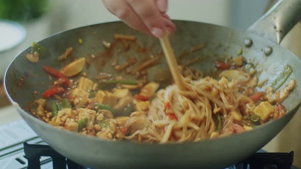 Woman mixing delicious wok noodles with chopsticks