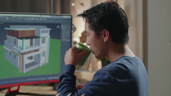 Close Up Of Asian Male Engineer Drinking Coffee While Designing House On A Desktop At Home