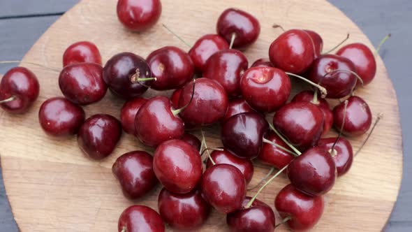 Hand puts cherries on wooden board close up