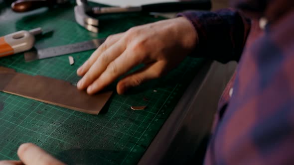 The Process of Manufacturing a Leather Wallet Handmade. The Craftsman Cut Off a Piece of Leather