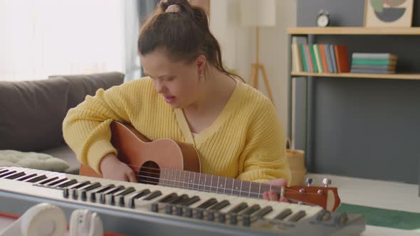 Girl with Down Syndrome Playing Guitar and Singing at Home