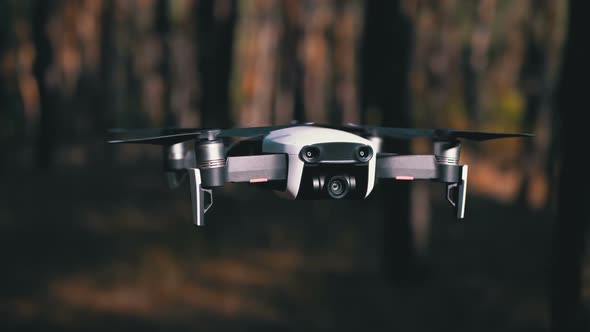 Drone with a Camera Hovers in the Air. Flies Above the Ground in the Forest. Slow Motion