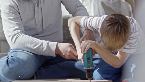 Man Helping Boy with Electric Screwdriver alt