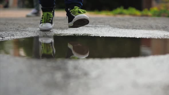 Close-up, Low Angle, Unrecognizable Kids Running Through Puddles Summer Day After Rain