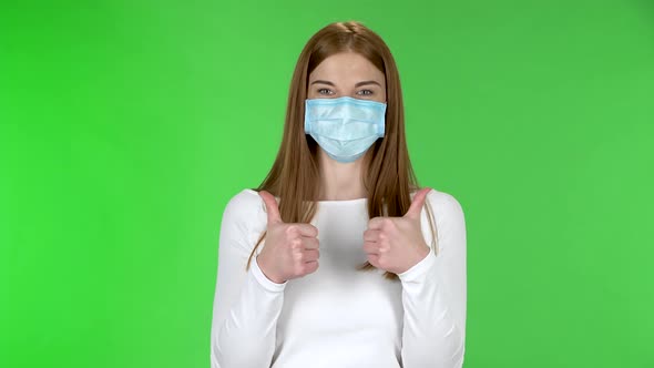 Portrait of Happy Pretty Young Girl in Medical Protective Face Mask Looking at Camera and Showing