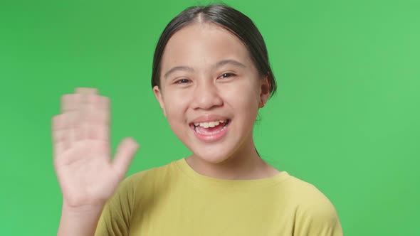 The happy young Asian man waving hand while standing on green screen in the studio alt