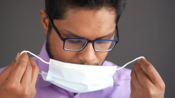 Young Asian Man Putting Surgical Face Mask Indoor