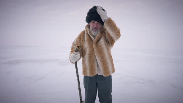 Portrait of Confident Indigenous Old Bearded Man Standing on Icy Frozen Arctic Ocean Looking at