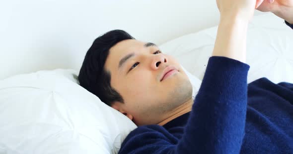 Man using mobile phone while relaxing on bed 4k