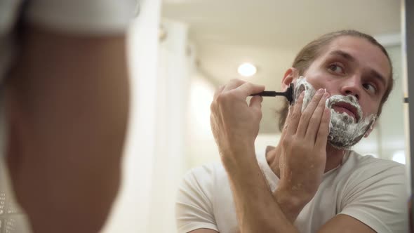 Man Shaving Beard With Razor In Bathroom