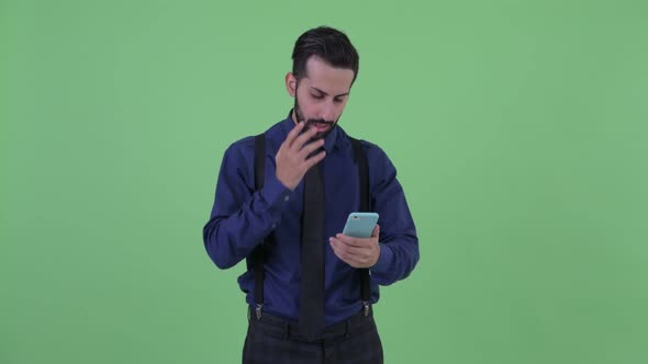 Stressed Young Bearded Persian Businessman Using Phone and Getting Bad News