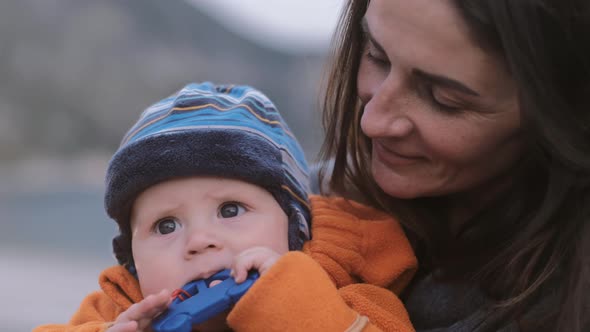 Portrait Woman with a child on nature in autumn. Mother with son in orange jumpsuit with a toy