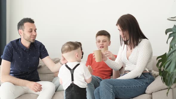 A Happy Friendly Family with Three Children is Drinking Tea in the Living Room
