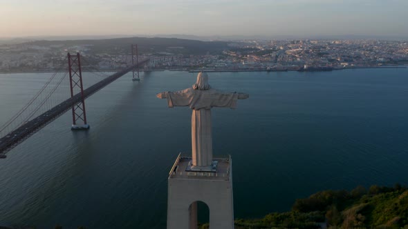 Back Aerial View of Sanctuary of Christ the King Statue with Ponte 25 De Abril Red Bridge in Lisbon