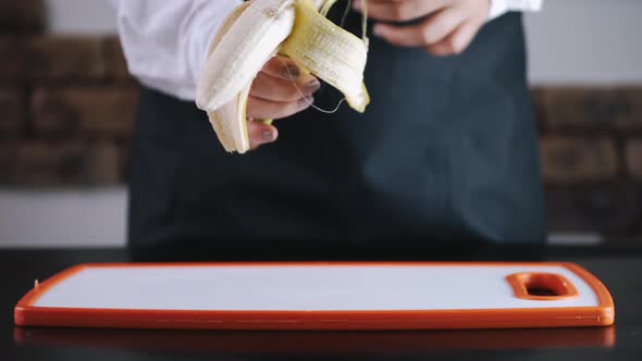 The Chef Is Peeling a Banana From a Skin Over a Cutting Board