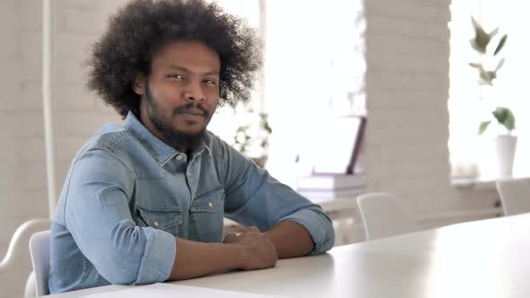 Thumbs Down By Creative African Man Looking at Camera at Work