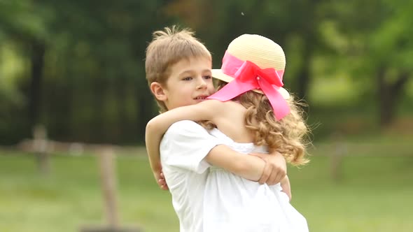 Little Boy Takes the Girl in Her Arms and They so Spin Around in the Park. Slow Motion