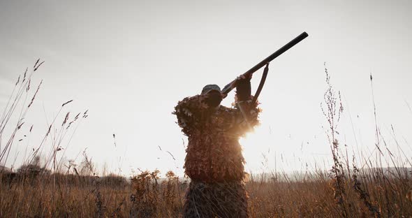 Hunter Aims the Target With Rifle in the Field at Foggy Morning or Sunny Autumn Evening