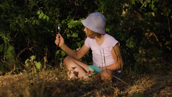 Girl Naturalist Seated Down Explores the Life Plants and Insects with Magnifying Glass Take Notes