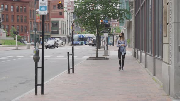 Girl with black face mask walks in barren street during global pandemic, USA