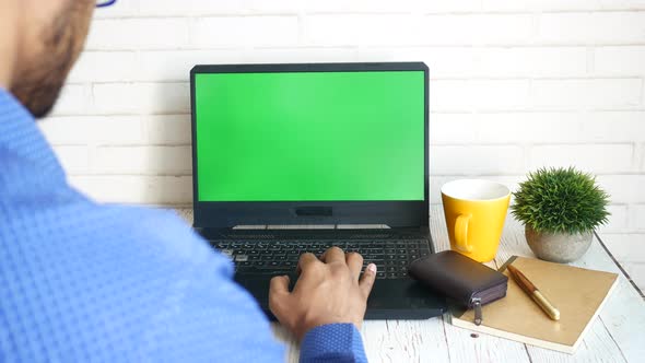 Rear View of Young Man Using Laptop with Blank Screen on Office Desk