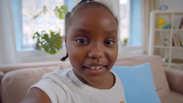 African American Preteen Girl Making Video Call Waving Hello Sitting on Sofa at Home