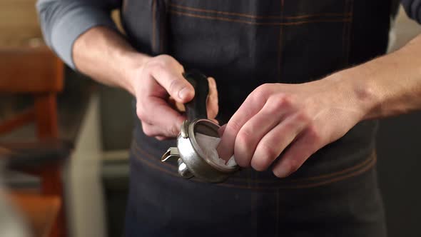 Closeup of a Male Barista Wipes a Portafilter for Ground Coffee with a Napkin