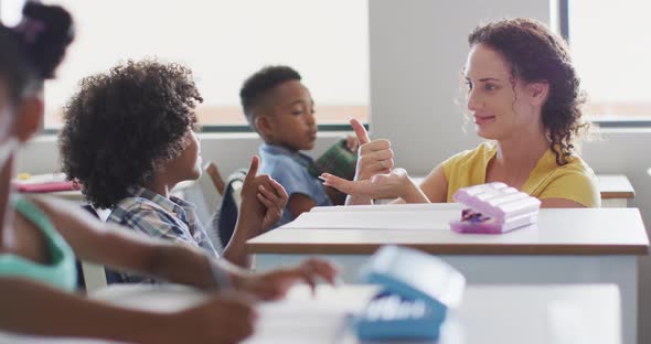 Video of happy caucasian female teacher learning math to african american boy