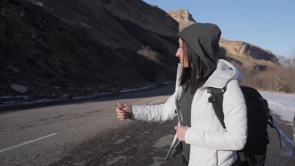 Tourist Girl with a Large Backpack Hitchhiking on a Lonely Rural Road. Journey Autostopem Alone