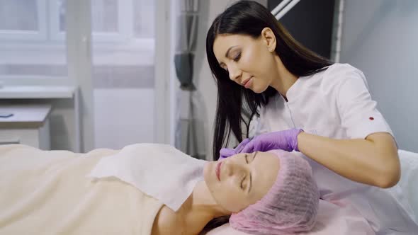 A cosmetologist makes injections for a woman in a beauty center. Mesotherapy.
