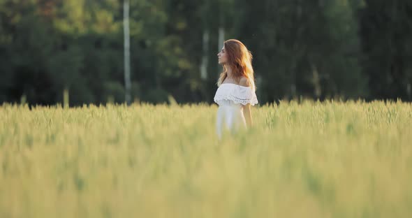 Pretty Girl Walks Through a Green Wheat Field