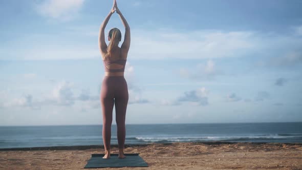 Backside View of Woman Does Yoga Exercises Stretches on Beach Slow Motion