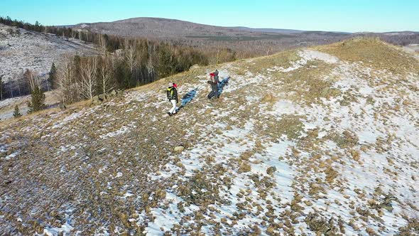 Aerial  Middleaged Couple Go Hiking in the Alpine Winter Mountains