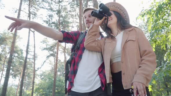 Young Handsome Bearded Man Pointing Away and Talking To Charming Beautiful Woman in Hat Looking