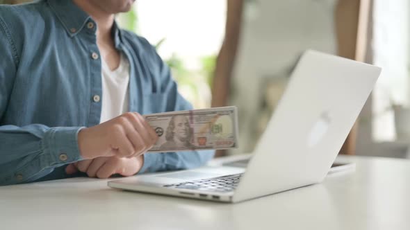 Close Up of Man Investing Dollars Through Laptop