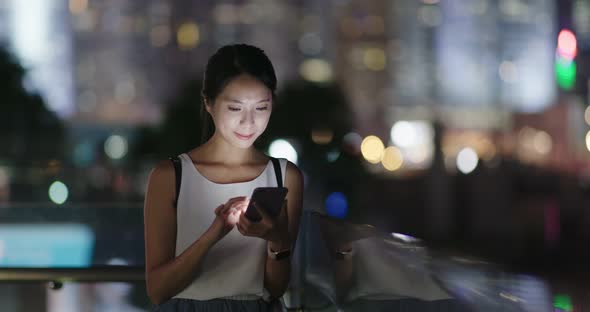 Woman use of mobile phone in city at night