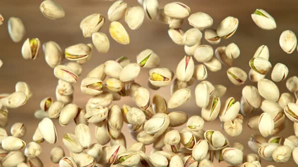 Super Slow Motion Shot of Flying Pistachios After Being Exploded on Wooden Background at 1000Fps.