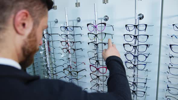 Man shopping for glasses in store. Handsome man measures glasses for vision in store